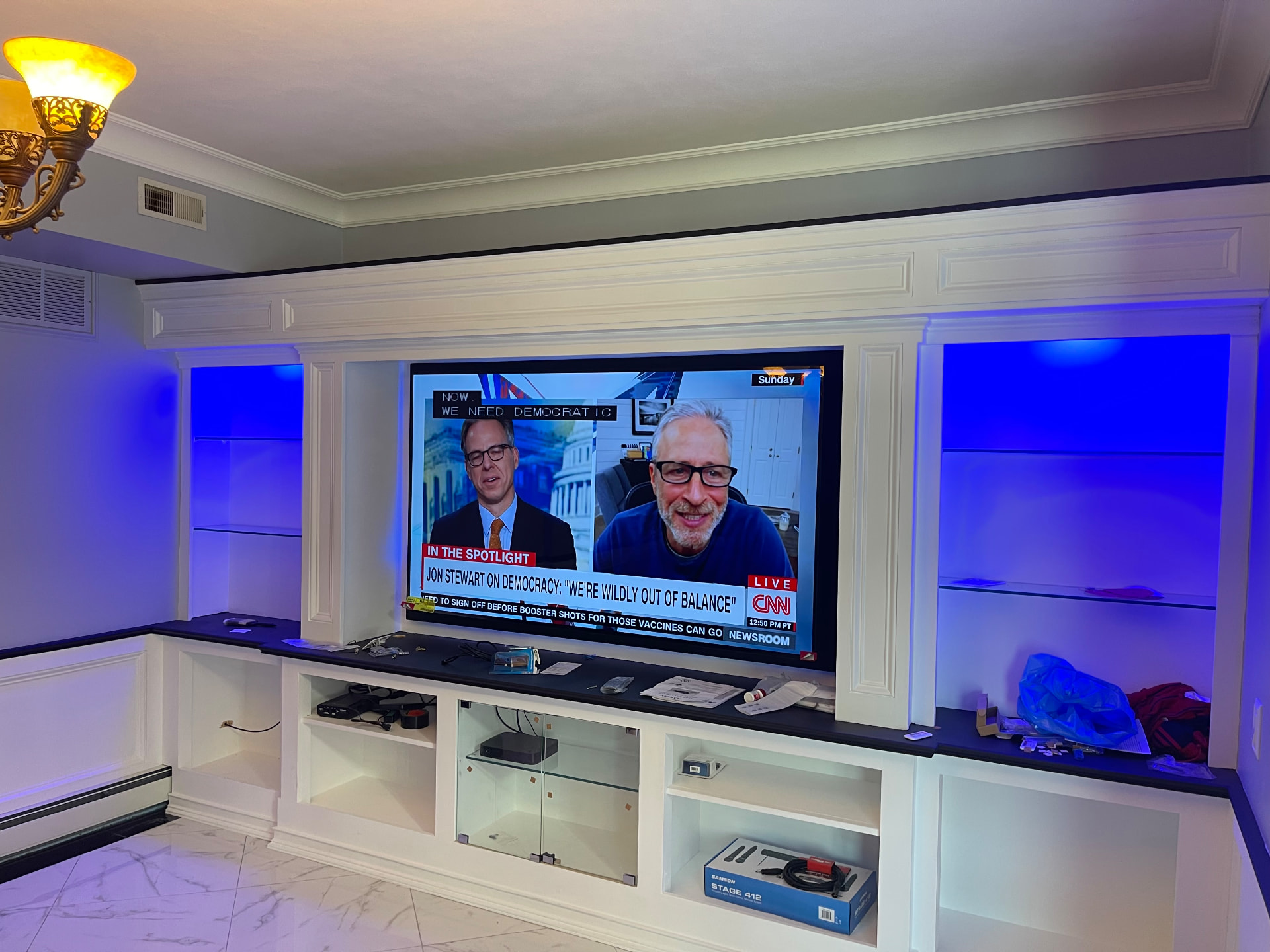 Custom white media wall with built-in shelving and LED accent lighting
