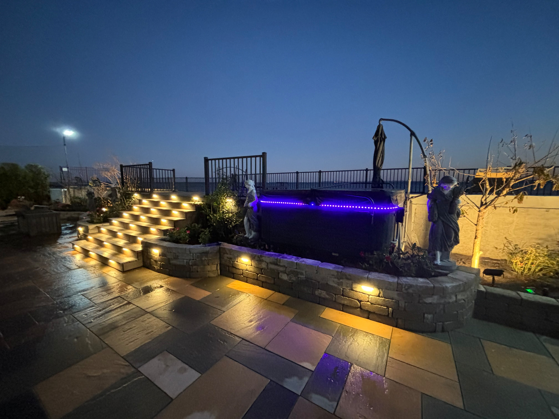 Bluestone patio with lit stone steps and retaining wall at dusk