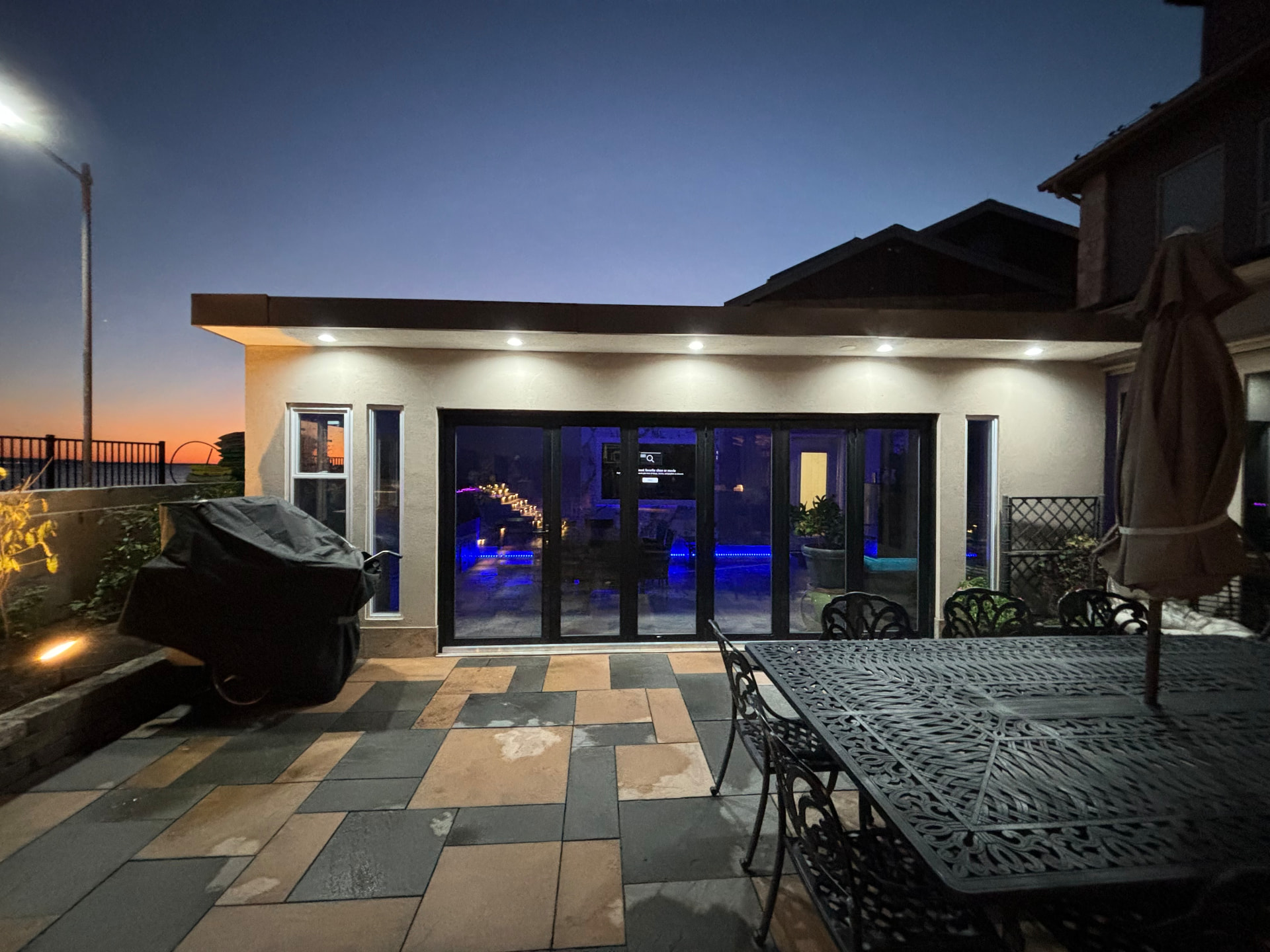 Rear addition with glass doors and stone patio at dusk