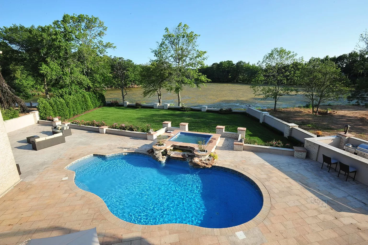 Freeform swimming pool with spa, waterfall, and paver patio